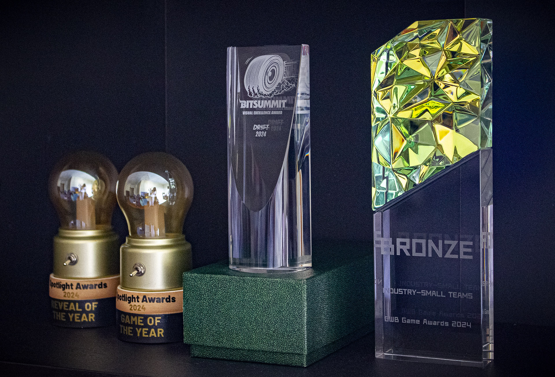 The following award on a shelf: BitSummit Drift Visual Excellence Award Winner; Tencent GWB Bronze Award Winner; Spotlight Awards 24: Game of the Year Award Winner, Reveal of the Year Award Winner